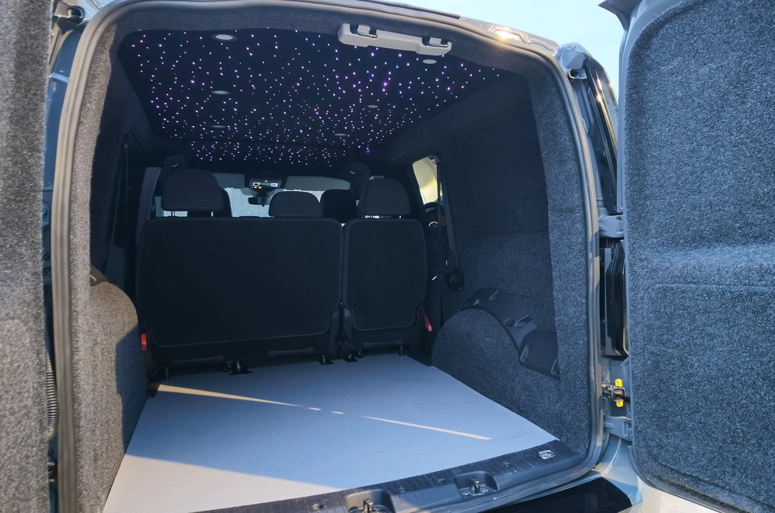 Purple and white fibre-optic lights in the roof lining of a carpet-lined van